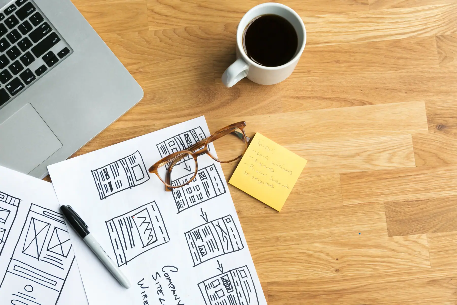 Designer's desk with coffee and wireframe sketches