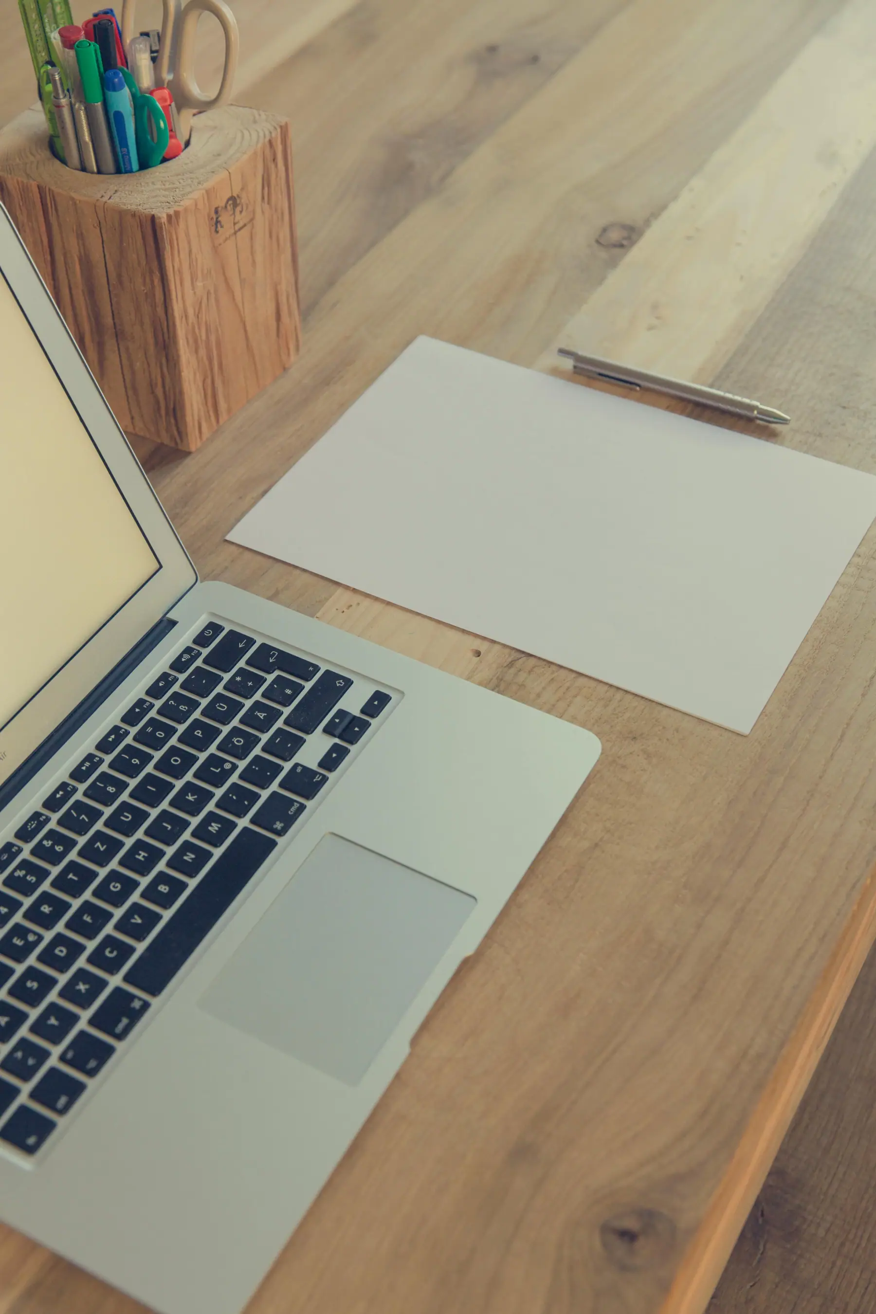 Laptop and blank paper on a wooden desk
